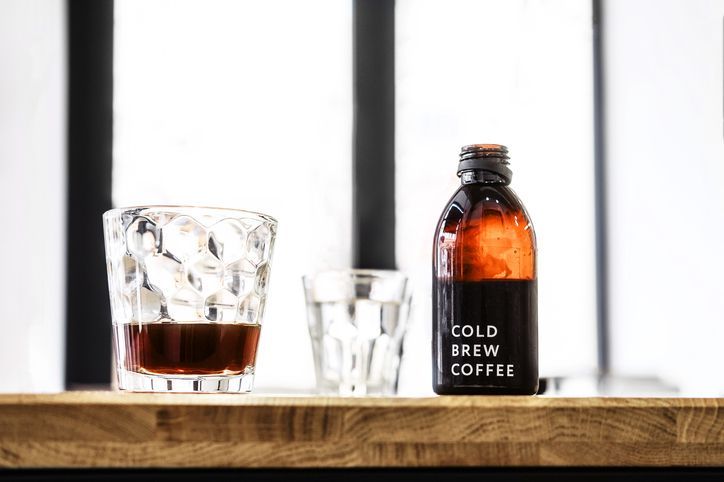 Fresh hot coffee being poured into a cup from a stainless steel french press in a trendy cafe