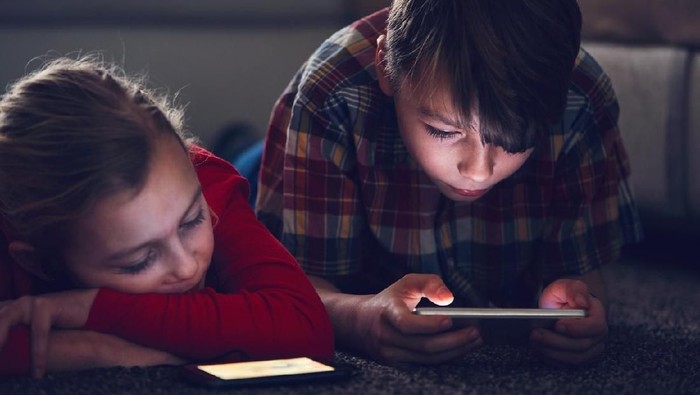 Little girl and boy watching video or playing games on their smart phones.
