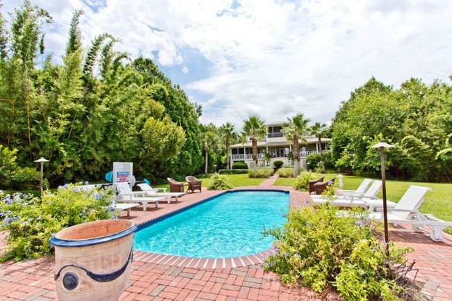 Halaman belakang rumah yang sangat luas. Terdapat kolam renang dan beberapa set kursi santai. Foto: dok. The Sun