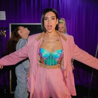 Pulasan eyeshadow oranye yang bold di daerah mata ini merupakan karya makeup artist Francesca Angelina Brazzo. Blush peach dan lipstik oranye membuat wajahnya tampak segar.  Foto: Instagram @dualipa