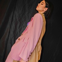 Penampilannya edgy dibalut setelan oversized berwarna pink dengan aksen two-tone coklat di bagian kerah hingga belakang jas. Foto: Instagram @dualipa