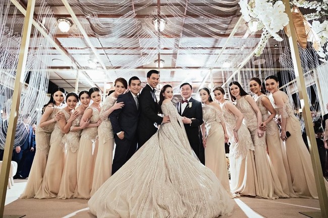 Pesta pernikahan Paetongtarn Shinawatra digelar dengan dekorasi serba putih. Sang mempelai wanita pun tersenyum bahagia saat berpose bersama ayahnya dan para bridesmaid atau pengiring pengantin meskipun tanpa ibunya. Thaksin memang menceraikan istrinya atau ibu dari anak-anaknya. Kabarnya perceraian itu terjadi untuk menyelamatkan hartanya yang diambil alih negara atas korupsi yang telah dilakukannya. Foto: Instagram @ingshin21