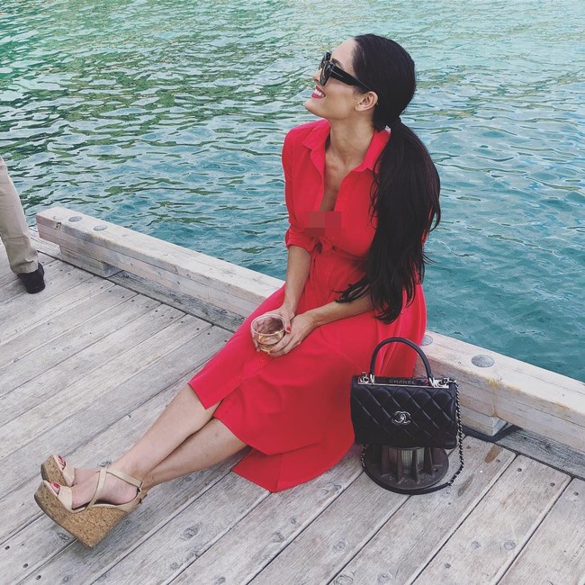 Ia juga mengoleksi tas Chanel. Seperti Chanel flap-bag hitam ini yang berpadu apik dengan shirt dress merah dan wedges coklat. (Foto: Instagram @thenikkibella)