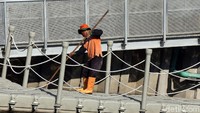 Selain menyisiri kali untuk mengumpulkan sampah, petugas juga menyapu area di sekitar jembatan agar terbebas dari sampah yang berserakan.