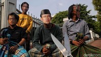 Aksi teatrikal ini dilakukan sejak pukul 15.00 WIB di depan Gedung MA, Jalan Medan Merdeka Utara, Jumat (29/3/2019). Poster Sunat Masal dibentangkan di pagar. Kemudian, empat orang pakai sarung dan duduk di kursi.