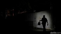 Seorang warga menggunakan cahaya dari telepon seluler saat berjalan di tengah malam, di Caracas. Foto: dok. Reuters