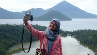 Wisatawan sedang berselfie dan menikmati pemandangan Pulau Maitara, Pulau Tidore, dan Danau Laguna di Desa Fitu, Ternate, Maluku Utara. 
