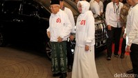 Maruf Amin nampak mengenakan jaket hoodie berwarna putih dengan lambang 01 dan sarung berwarna hijau.