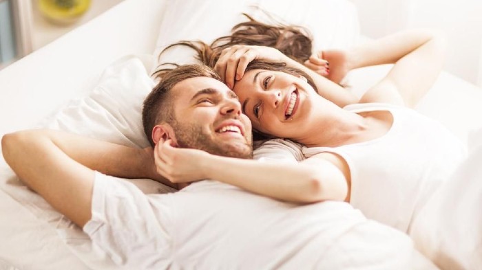 Affectionate young couple waking up in bed, early in the morning,