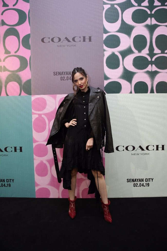 Nia Ramadhani muncul dalam balutan busana serba hitam nan edgy yang terdiri dari shirt dress dan bikers jacket kulit. Ibu tiga anak ini lalu menyempurnakan gayanya dengan lace ankle boots merah yang seksi. Foto: Dok. Coach