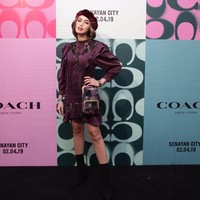 Jessica Iskandar mengandalkan tampilan yang chic dengan dress berhias ruffle marun yang senada dengan topi baret velvetnya. Tidak ketinggalan tas Coach selempang bermotif patchwork. Foto: Dok. Coach