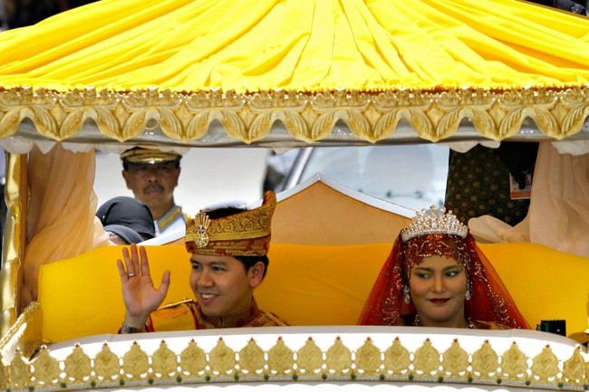 Setelah resmi menikah, pasangan pengantin Kesultanan Brunei ini naik mobil klasik berwarna kuning untuk berparade menyapa masyarakat yang antusias ingin melihat mereka. Pesta pernikahan pasangan putri dan pangeran Brunei ini sendiri dihadiri lebih dari 2.000 tamu undangan. Foto: AFP