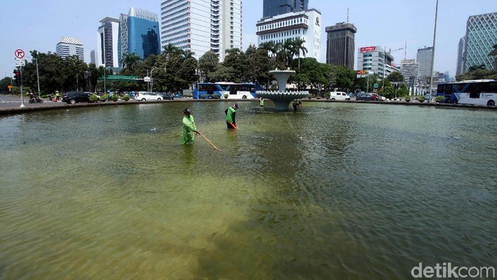 Petugas Dinas Kehutanan DKI Jakarta membersihkan kolam air mancur Patung Kuda, Jakarta Pusat, Kamis (4/4). Air mancur tersebut tampak penuh busa.