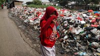 Seorang warga harus menutup hidungnya saat melintas area penuh sampah.