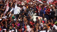 Jokowi bersama Iriana disambut meriah oleh para pendukung saat akan melaksanakan kampanye. Jokowi pun langsung menyalami para pendukung yang berdiri di sisi mobil Jeep yang ditumpanginya bersama Iriana.