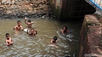 Mereka terlihat asyik bermain di kali meski airnya kotor.