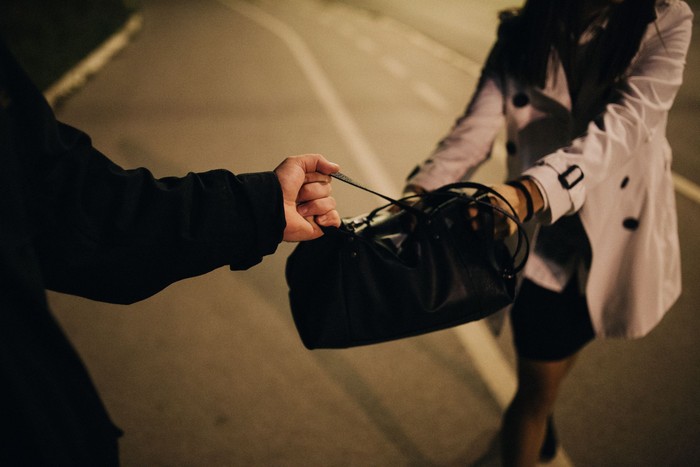 Two people, man and woman, criminal in action, purse robbery, cropped.