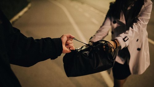 Two people, man and woman, criminal in action, purse robbery, cropped.