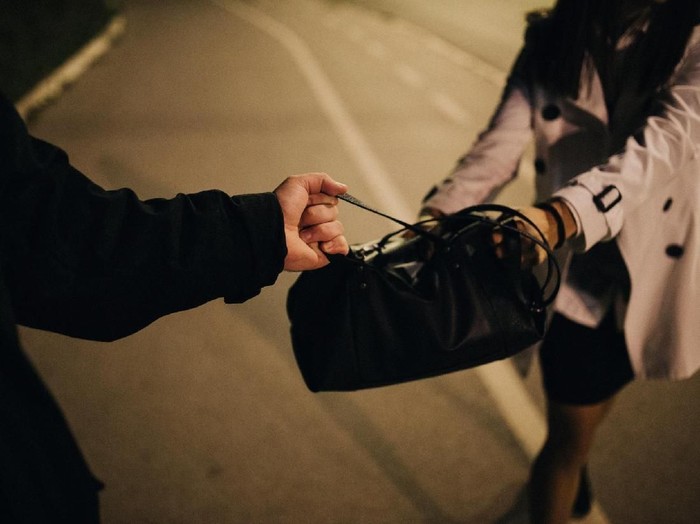 Two people, man and woman, criminal in action, purse robbery, cropped.