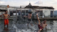 Anak-anak bermain di Mushola Waladuna yang terendam air laut kawasan Muara Baru, Jakarta Utara, Jumat (5/4).