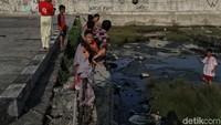Sesekali mereka harus mengambil bola yang masuk ke genangan air di pinggir jalan.