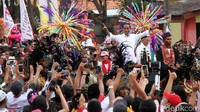 Jokowi mengacung-acungkan jari telunjuknya saat melintasi kerumunan massa.