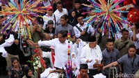 Jokowi dan Maruf melambaikan tangan dari delman ke arah massa yang telah menunggu pasangan itu sejak siang.
