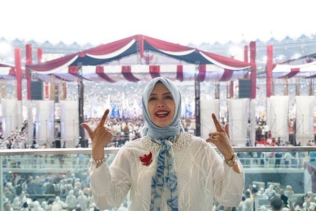 Menambah aksen kebiruan, ia memakai pattern scarf biru langit yang dipakai sebagai syal di lehernya. Ia pun memakai rok dan tas berwarna biru. Foto: Instagram @nurasiauno