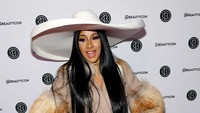 Cardi B tampil beda dengan busana penuh dengan bulu putih-coklat dan topi putih lebar. Noam Galai/Getty Images for Beautycon