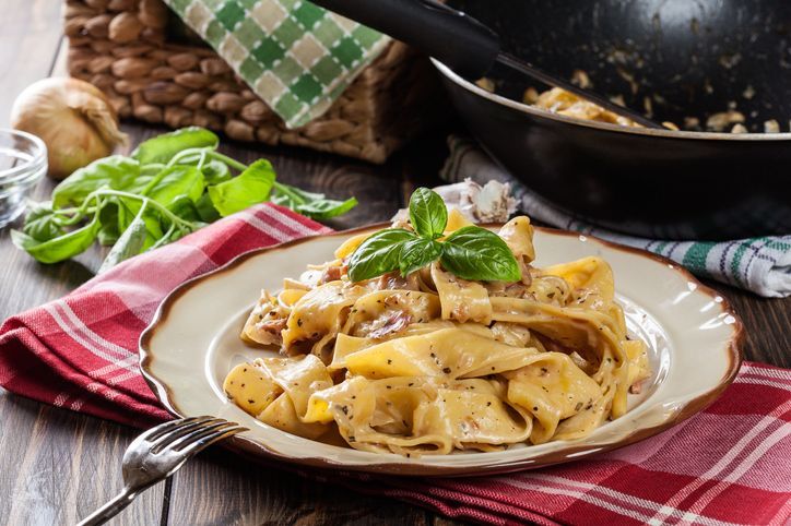 Pappardelle pasta with prosciutto and cheese sauce on a plate. Food and drink