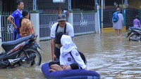 Banjir dikawasan itu juga membuat seorang anak terpaksa menggunakan kasur angin untuk menuju ke sekolahnya. Kreatif juga ya.