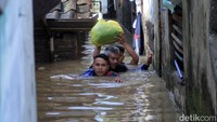 Warga mengungsi melewati gang yang terendam banjir setinggi leher.
