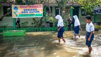 Meski sekolah direndam banjir, ujian sekolah tetap diselenggarakan.