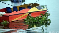 Sebagian pekerja harus nyemplung ke dalam waduk untuk membersihkan eceng gondok yang tumbuh di permukaan air.