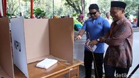 Seorang tuna netra dibantu petugas menuju bilik suara.