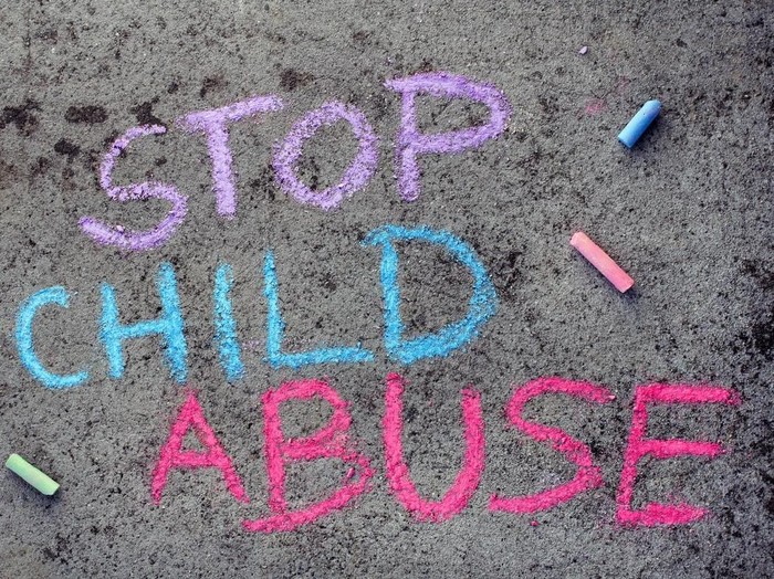 Colorful chalk drawing on asphalt: words STOP CHILD ABUSE