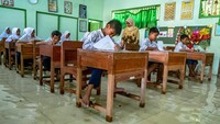 Sejumlah siswa SD kelas VI mengikuti ujian sekolah di ruang kelas yang terendam banjir di SD Negeri Sayung 4, Sayung, Demak, Jawa Tengah, Rabu (10/4/2019).