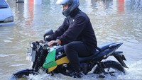 Pengendara sepeda motor nekat menerobos banjir.