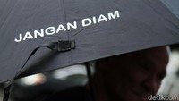 Mereka berdiri di seberang Istana dengan menggunakan payung hitam.