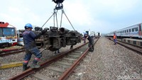 Para pekerja KAI sedang memindahkan baigan roda kereta api.