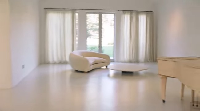 Ruang santai dengan grand piano, yang lagi-lagi, didominasi palet monokrom. Foto: Screenshot YouTube/Vogue