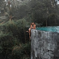 Fotografer menangkap Kelly berpose dengan berani, menggantung di sisi kolam yang menghadap ke jurang sambil mencium kekasihnya yang ada di dalam air. Kody tampak memegang tangan Kelly, sementara tubuh dan kakinya menggantung bebas. Foto: Instagram @positravelty