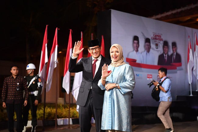 Pada Debat Pilpres 2019 terakhir hari ini 13 April 2019, Nur Asia Uno konsisten dengan busana biru. Kali ini ia memilih tunik bernuansa biru dengan jenis kain yang mengkilat. Wanita yang akrab disapa Mpok Nur itu memadukan tunik biru dengan hijab segi empat dan celana pensil berwarna beige. Bros garuda berwarna merah tak ketinggalan bertengger di dadanya. Foto: Antara Foto/Rivan Awal Lingga