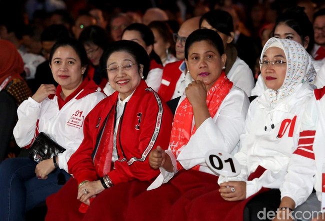 Bukan hanya Iriana yang tampil dengan aksesori bertuliskan 01, istri Maruf Amin, Wury Estu Handayani, mengenakan jaket putih yang juga berhias tulisan #01. Tampil total mendukung suami, ia pun memakai jilbab putih dari scarf dengan motif tulisan #01. Foto: Agung Pambudhy