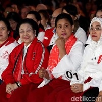 Bukan hanya Iriana yang tampil dengan aksesori bertuliskan 01, istri Maruf Amin, Wury Estu Handayani, mengenakan jaket putih yang juga berhias tulisan #01. Tampil total mendukung suami, ia pun memakai jilbab putih dari scarf dengan motif tulisan #01. Foto: Agung Pambudhy