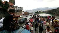 Orang-orang mengumpulkan air di Caracas.