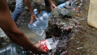 Warga mengambil air dari sungai di Caracas.