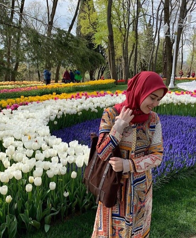 Ayu tampak berbeda saat mengenakan dress bermotif etnik dipadukan dengan hijab warna merah. Gaya hijab yang dipilihnya cukup sederhana dan cocok dipakai untuk traveling. Foto: Dok. Instagram Ayu Ting Ting