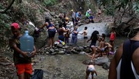 Orang-orang mencuci pakaian dan mandi dengan air dari sungai di Caracas.