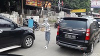 Dayat milih beraksi di tengah jalan antara baris kendaraan. Kinclong banget kan, kebayang nggak teriknya matahari waktu Dayat jadi manusia silver? (Foto: Rosmha/detikHealth)